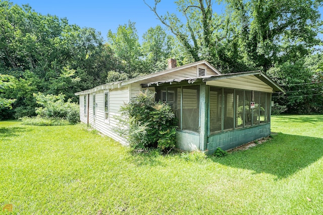 view of side of home featuring a sunroom and a lawn