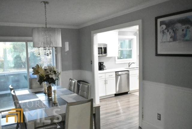 dining area featuring an inviting chandelier, light hardwood / wood-style floors, and ornamental molding