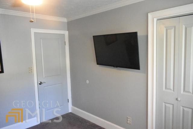 interior space featuring ornamental molding, a closet, and dark carpet