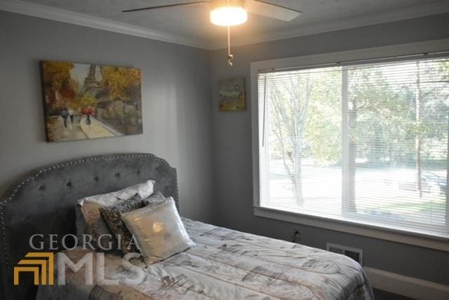 bedroom featuring ceiling fan, ornamental molding, and multiple windows