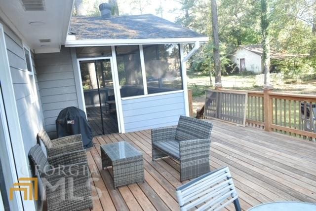 deck featuring a sunroom and a grill