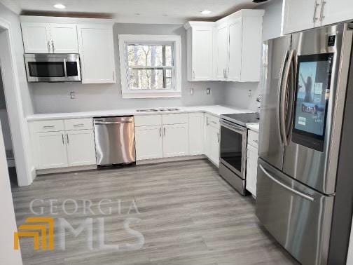 kitchen with white cabinetry, light wood-type flooring, and stainless steel appliances