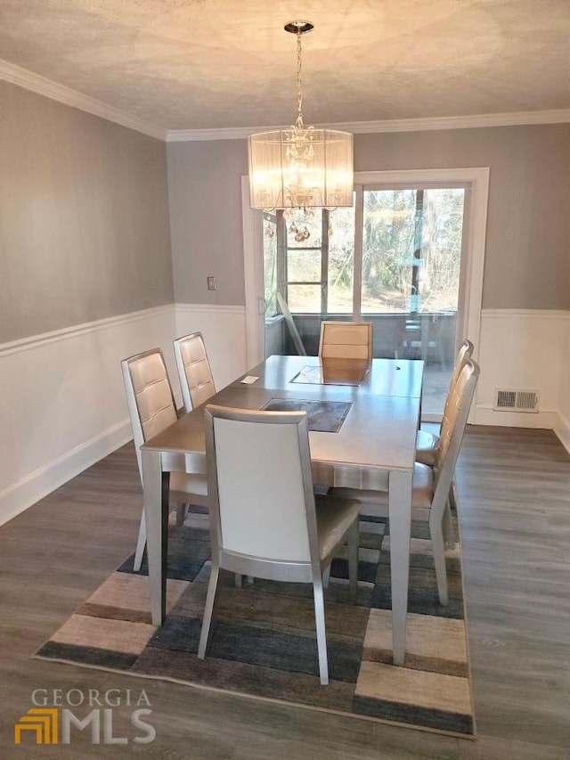 dining room featuring an inviting chandelier, crown molding, and dark hardwood / wood-style floors