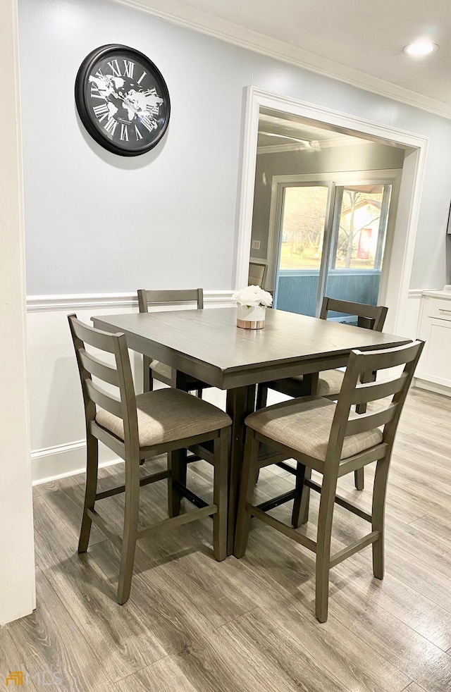 dining room with crown molding and light wood-type flooring