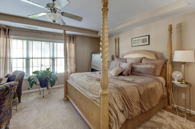 bedroom featuring light carpet, a tray ceiling, and ceiling fan