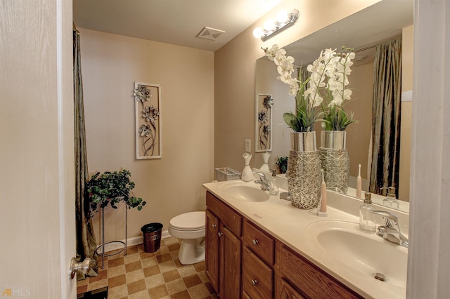 bathroom with dual sinks, large vanity, tile floors, and toilet