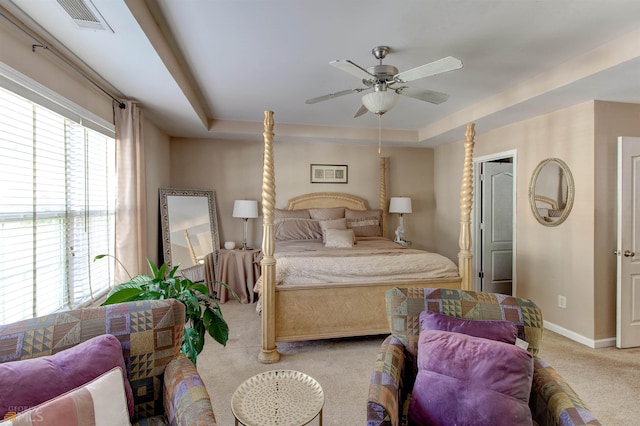 carpeted bedroom with a tray ceiling and ceiling fan