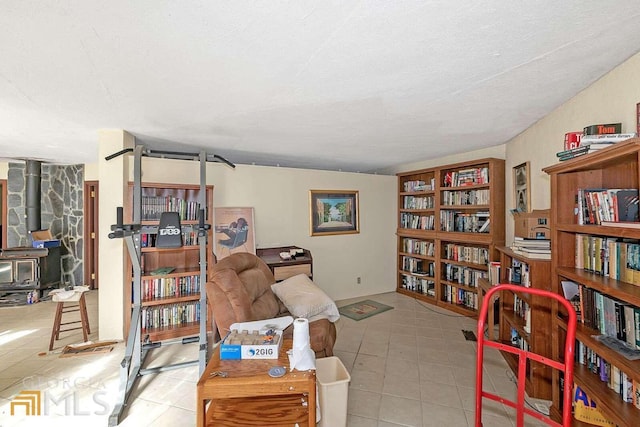 sitting room with a textured ceiling, light tile flooring, and a wood stove