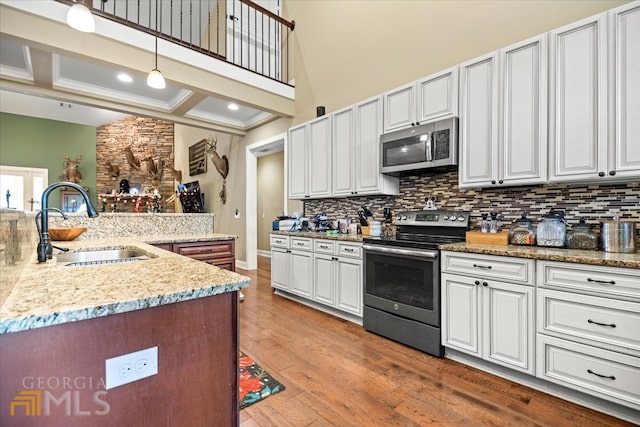 kitchen with white cabinets, hardwood / wood-style flooring, pendant lighting, and appliances with stainless steel finishes