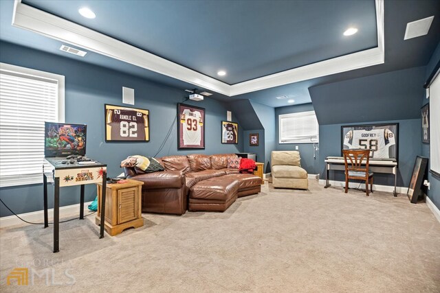 interior space featuring a raised ceiling, plenty of natural light, and light carpet