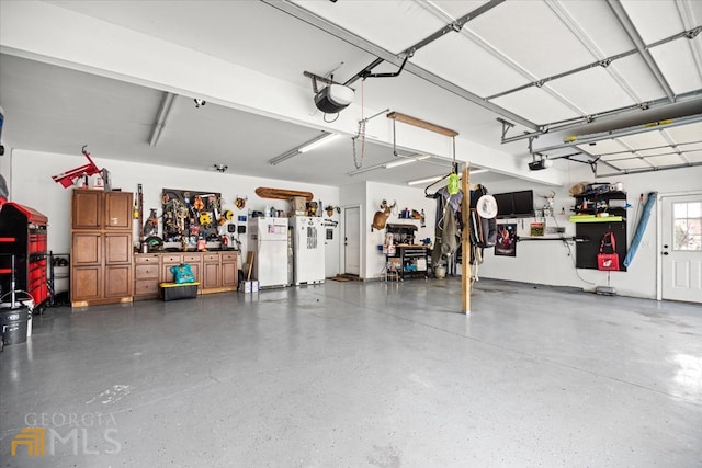 garage featuring a garage door opener, a workshop area, and white fridge