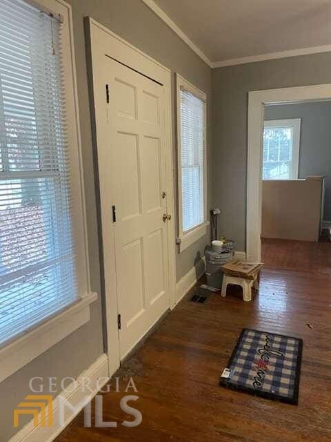 entrance foyer featuring a wealth of natural light, ornamental molding, and dark hardwood / wood-style floors