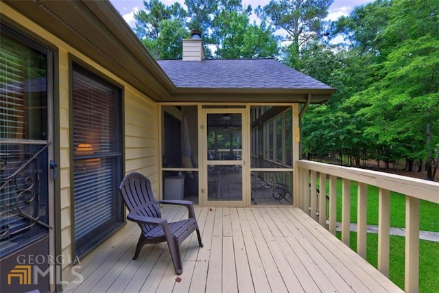 wooden deck featuring a lawn and a sunroom