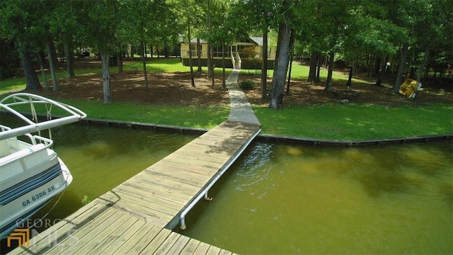 view of dock with a water view and a yard