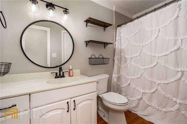 bathroom featuring wood-type flooring, a textured ceiling, toilet, vanity, and ornamental molding