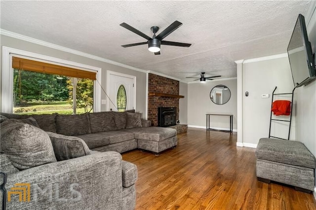 living room with dark wood-type flooring, ceiling fan, brick wall, a fireplace, and a textured ceiling