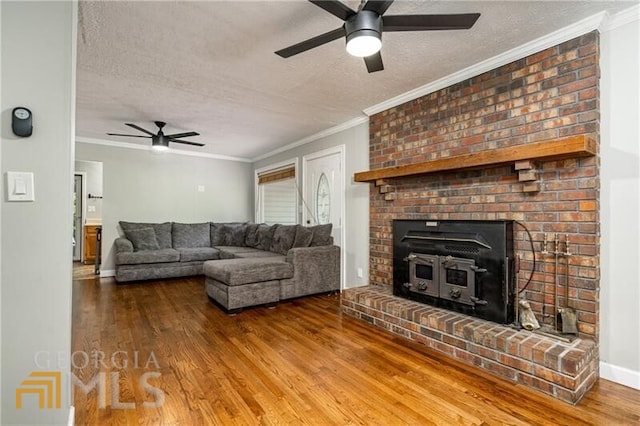 living room with ceiling fan, a textured ceiling, dark wood-type flooring, and a brick fireplace