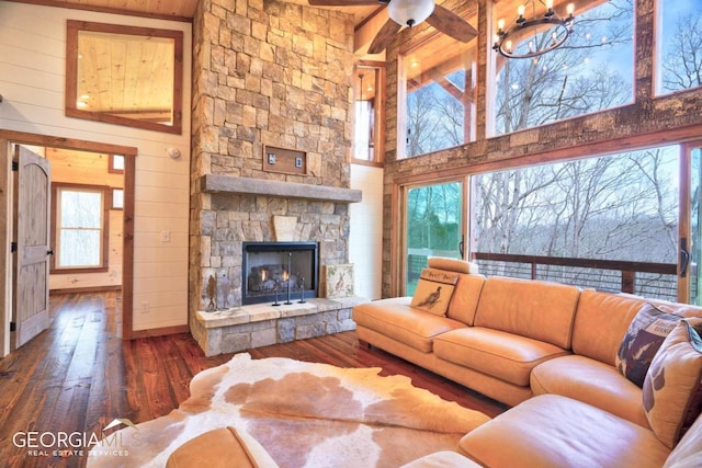 living room with ceiling fan, dark wood-type flooring, a towering ceiling, and a fireplace