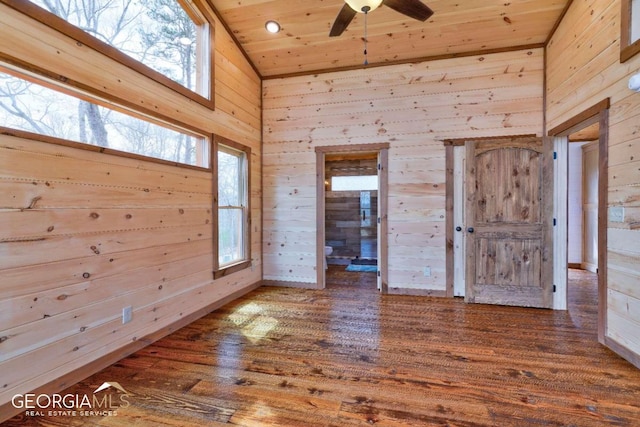 spare room with high vaulted ceiling, wooden ceiling, ceiling fan, wooden walls, and dark wood-type flooring