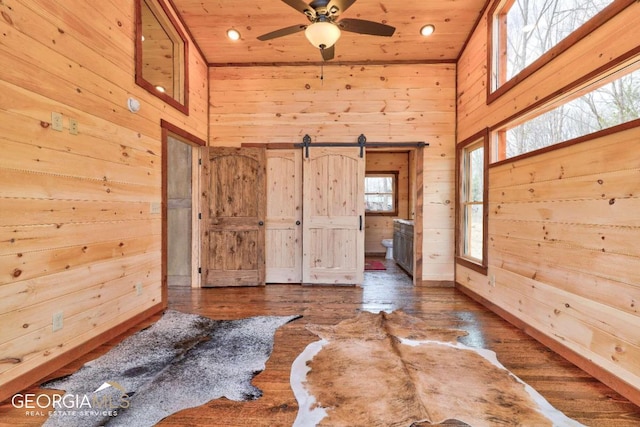 interior space with ceiling fan, wood ceiling, a high ceiling, and dark hardwood / wood-style floors