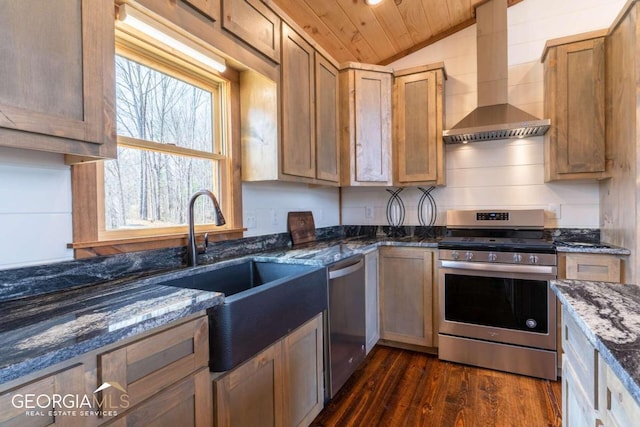 kitchen featuring appliances with stainless steel finishes, wall chimney exhaust hood, dark stone countertops, vaulted ceiling, and dark hardwood / wood-style floors