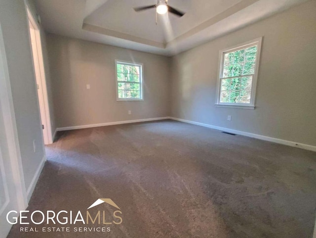 carpeted empty room featuring a raised ceiling and ceiling fan