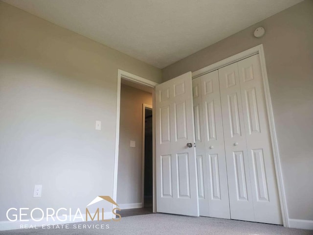 unfurnished bedroom featuring light carpet and a closet