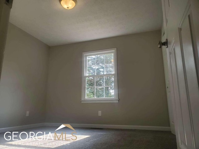 carpeted spare room featuring a textured ceiling