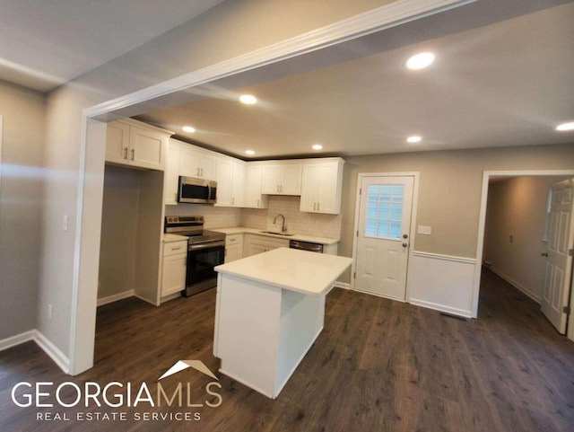 kitchen featuring a center island, dark hardwood / wood-style flooring, white cabinetry, appliances with stainless steel finishes, and sink