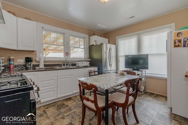 kitchen featuring white cabinetry, tile floors, stainless steel fridge, and sink