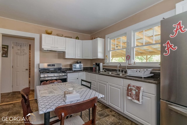 kitchen with white cabinets, dark tile flooring, stainless steel appliances, and sink