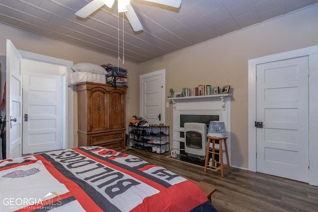 bedroom featuring ceiling fan, dark wood-type flooring, and a fireplace