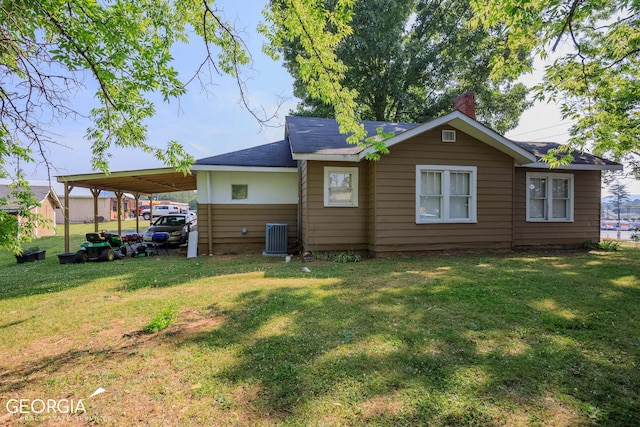 back of house featuring central AC unit, a carport, and a yard