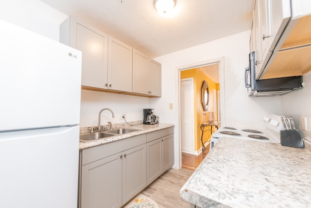 kitchen featuring range, white refrigerator, gray cabinetry, light wood-type flooring, and sink