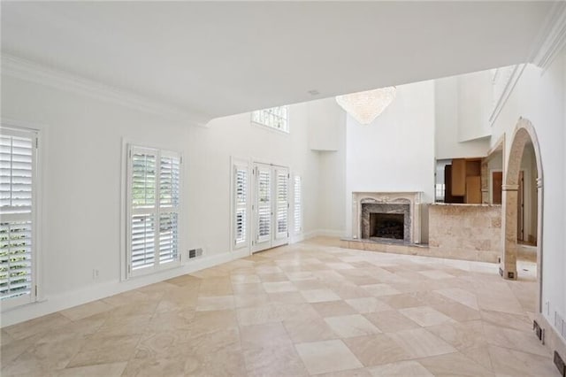 unfurnished living room with a high end fireplace, light tile floors, and a healthy amount of sunlight