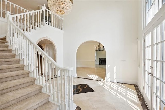 interior space with french doors, a chandelier, light tile floors, and a towering ceiling