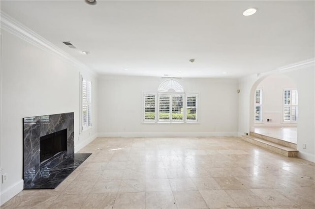 unfurnished living room featuring light tile floors, a high end fireplace, and a wealth of natural light