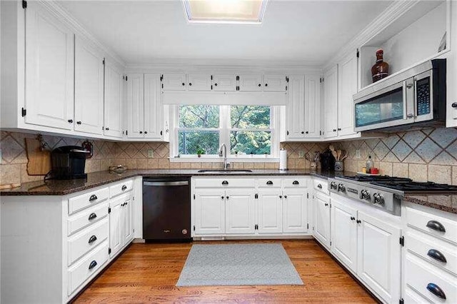 kitchen featuring white cabinets, appliances with stainless steel finishes, dark stone countertops, and sink