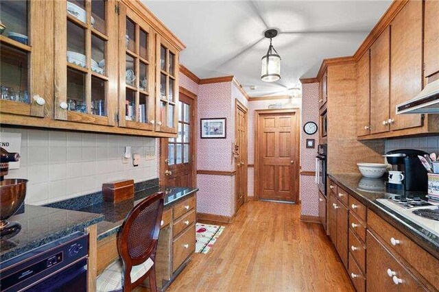 kitchen with light hardwood / wood-style floors, crown molding, backsplash, black oven, and pendant lighting