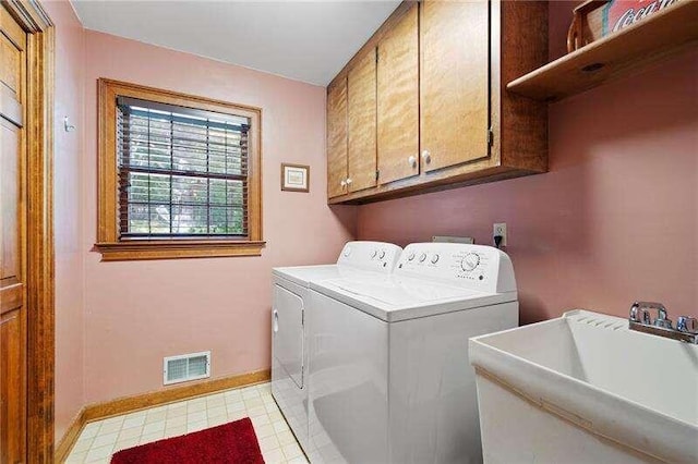 washroom with washing machine and dryer, sink, cabinets, and light tile floors