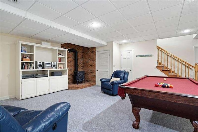 game room with brick wall, a paneled ceiling, a wood stove, pool table, and carpet floors