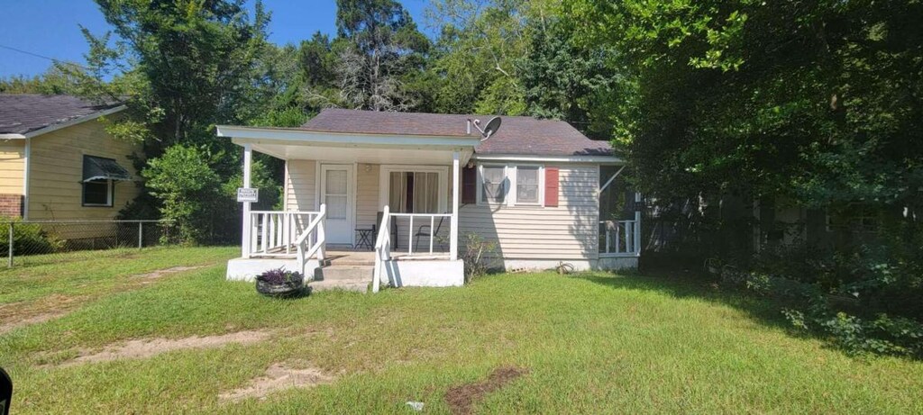 back of property featuring covered porch and a lawn