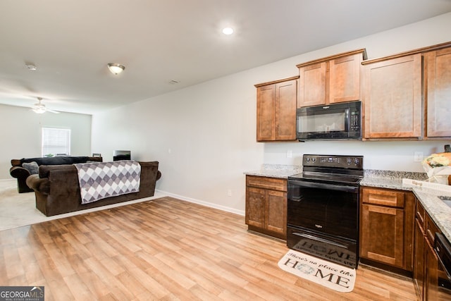 kitchen with ceiling fan, light wood-type flooring, light stone counters, and black appliances