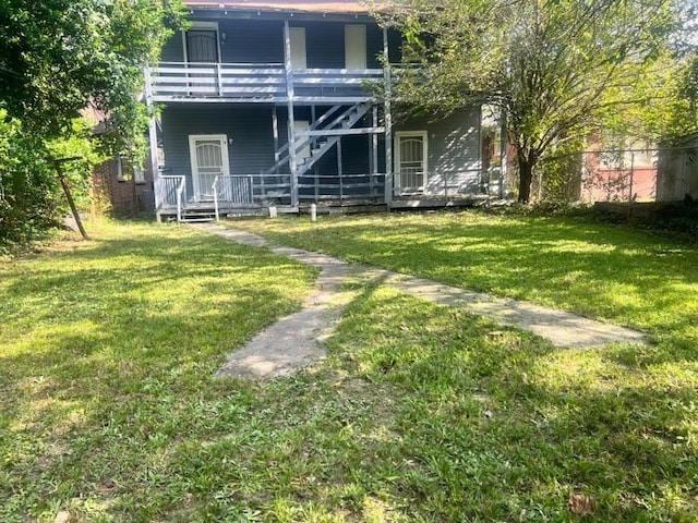 back of property with a balcony and a lawn