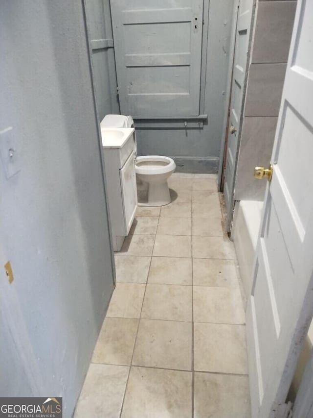 bathroom featuring tile patterned floors, toilet, a washtub, and vanity