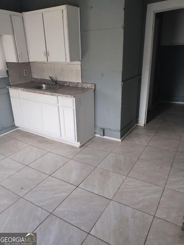 kitchen with light tile patterned floors, white cabinetry, sink, and decorative backsplash