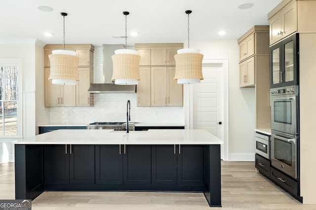 kitchen featuring pendant lighting, a kitchen island with sink, light brown cabinets, and wall chimney range hood