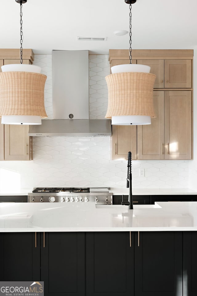 kitchen with pendant lighting, wall chimney exhaust hood, stainless steel gas stovetop, and decorative backsplash