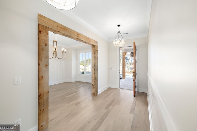 entrance foyer with crown molding, a chandelier, and light hardwood / wood-style floors