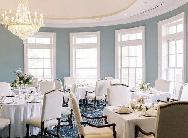 dining area with a chandelier, a raised ceiling, and a healthy amount of sunlight